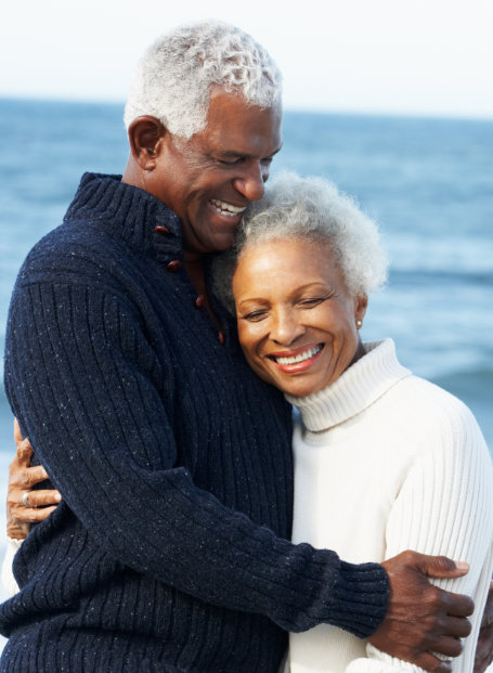 old African american couple hugging and smiling at the beach